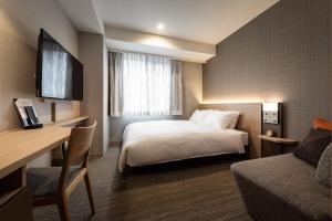 a hotel room with a bed and a desk at Nishitetsu Hotel Croom Nagoya in Nagoya