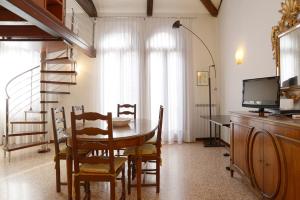 a dining room with a table and chairs and a television at Sunny Canal a/c wifi in Venice