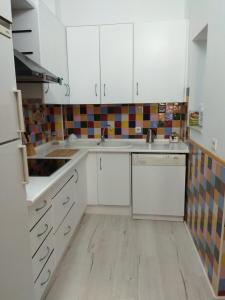 eine Küche mit weißen Schränken und Holzböden in der Unterkunft Abá apartamento in Almería