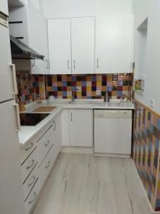 a kitchen with white cabinets and a wooden floor at Abá apartamento in Almería