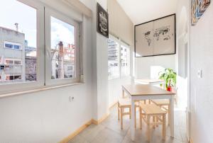 een eetkamer met een tafel, stoelen en ramen bij LX Sweet Home in Lissabon
