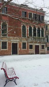 un banco cubierto de nieve frente a un edificio de ladrillo en Cà Sardi, en Venecia