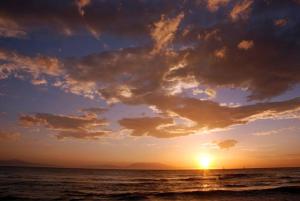 a sunset on the beach with the sun setting at Kiwi Kastle in Nea Fokea