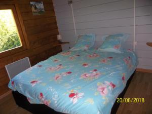 Una cama con un edredón azul con flores. en ALAGUYAUDER LE GITE DE L'ETANCHEE, en Châtillon-sur-Broué