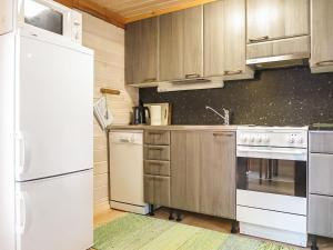 a kitchen with white appliances and wooden cabinets at Holiday Home Ruska by Interhome in Kyrö +10 photos