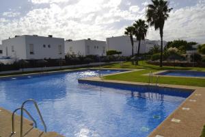 een groot blauw zwembad met gebouwen op de achtergrond bij Apartamento Cabo de Gata in Retamar