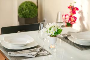 a table with plates and glasses and a vase of flowers at Apartments Sata Olimpic Village Area in Barcelona