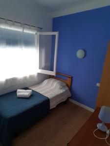 a blue bedroom with a bed and a window at Hostal Pancheta in San Pol de Mar