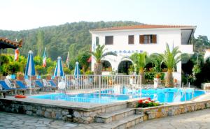einen Pool in einem Resort mit Stühlen und Sonnenschirmen in der Unterkunft Afroditi in Panormos Skopelos
