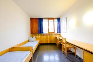 Cette chambre comprend deux lits, une table et des chaises. dans l'établissement Internationales Jugendgästehaus Dachau, à Dachau