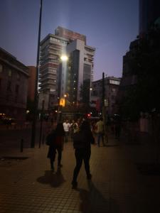 un grupo de personas caminando por una calle de la ciudad por la noche en Lindo departamento a pasos del Centro comercial Costanera Center, en Santiago