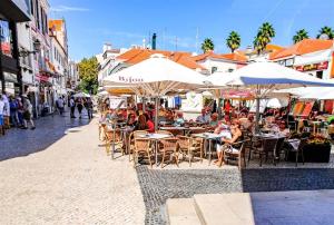 a group of people sitting at tables under umbrellas on a street at Cascais Handsome Apartment in Cascais