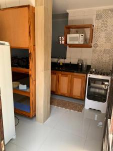 uma cozinha com um fogão branco e um micro-ondas em CASA PÔR DO SOL 1 em Arraial do Cabo
