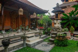 a garden in front of a house with potted plants at Sekar Waru Homestay in Sanur