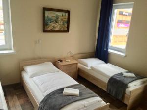 two beds in a room with two windows at Pokoje Goscinne ATENA in Gubin