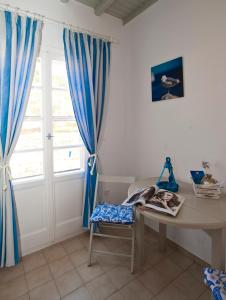 Habitación con escritorio y ventana con cortinas azules. en Gryparis' Club Apartments en Mykonos
