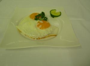 un plato blanco con un huevo y una rebanada de aguacate en Cafe und Pension Blohm, en Greifswald