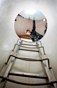 a man is standing on a ladder in a mirror at Utter Inn in Västerås