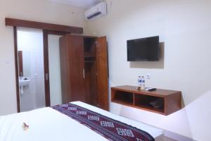 a bedroom with a bed and a tv on the wall at Sekar Waru Homestay in Sanur