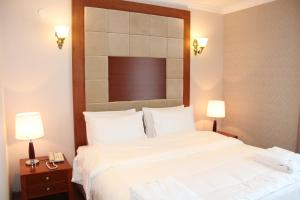 a bedroom with a large white bed and two lamps at Hotel Park Green in Poti