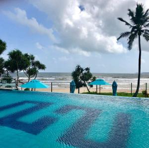 a swimming pool next to a beach with umbrellas at Twenty-Two Weligambay in Weligama