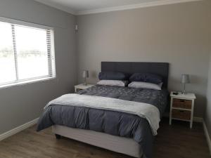 a bedroom with a bed with blue pillows and a window at 679 Morsvalla Way Langebaan Golf Estate in Langebaan