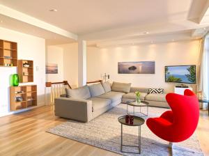 a living room with a couch and red chairs at Waterview Cloud***** in Ostseebad Sellin
