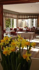 een vaas met gele bloemen in een kamer met tafels bij Logis Hotel Belle-Vue in Fouesnant