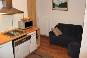 a kitchen with a microwave and a couch in a room at Apartments Koblar in Kranjska Gora