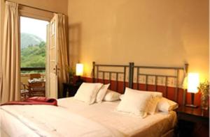 a bedroom with a bed with white pillows and a window at El Castillo de Mandl in La Cumbre