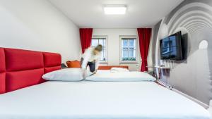 a woman standing on two beds in a hotel room at Hotel am Museum Köln in Cologne
