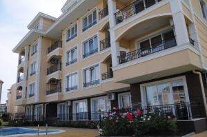 a large building with balconies and flowers in front of it at Apartments in RIF 3 in Ravda