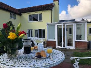 a table with a plate of bread and orange juice at Marsh View Cottage, Aldeburgh in Aldeburgh