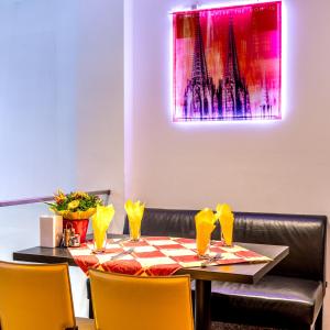 einen Esstisch mit gelben Stühlen und ein rosafarbenes Gemälde in der Unterkunft Hotel am Museum Köln in Köln