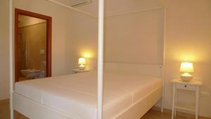 ein weißes Bett in einem Zimmer mit 2 Lampen an Tischen in der Unterkunft Il Sole in Maruggio