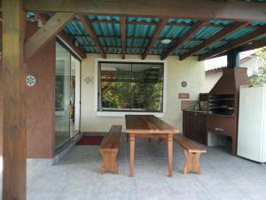a patio with a bench and a table and a refrigerator at Refúgio Vista Mar Praia da Gamboa - SC in Garopaba +30 photos