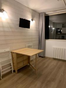 Habitación con mesa de madera y TV en la pared. en Studio des Cintes Blanques, en Aragnouet