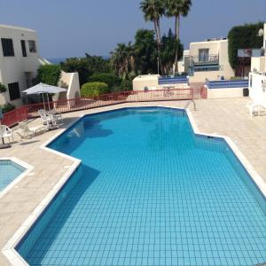 een groot zwembad met blauw water in een resort bij Pelagos Hill Apartment in Paphos City