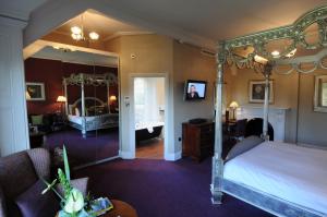 
a bedroom with a large bed and a large mirror at East Lodge Country House in Bakewell

