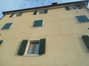 un edificio con finestre con persiane verdi di Appartamento Soldo a Castelletto di Brenzone