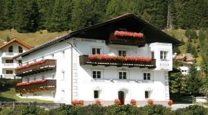 un bâtiment blanc avec des boîtes de fleurs sur ses fenêtres dans l'établissement Appartements Fliana Mathon/Ischgl, à Ischgl