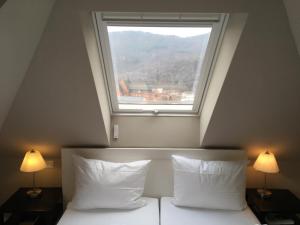 a bedroom with a window above a bed with two lamps at Villa Waldfrieden - Gästehaus zum Jugendstilhotel in Annweiler am Trifels
