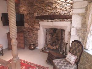 a living room with a stone fireplace with a chair at Swan Inn Lechlade in Lechlade