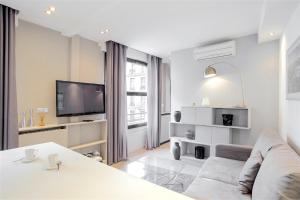 a white living room with a couch and a tv at Apartment Opéra / Galeries Lafayette in Paris