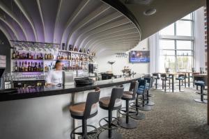 Eine Bar in einem Restaurant mit einer Frau hinter dem Tresen. in der Unterkunft Hôtel du Domaine, centre de villégiature et de congrès in Thetford Mines