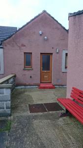 a red bench in front of a building with a door at Castleyards Apartment 12 in Kirkwall
