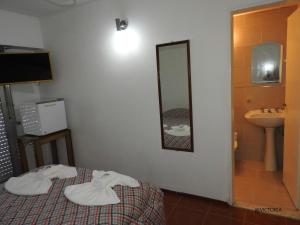Habitación con cama, lavabo y espejo. en Hotel Tiburones Club en Villa Gesell