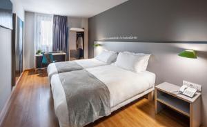 Un dormitorio con una gran cama blanca y una mesa. en ibis Styles Pamplona Noain, en Noáin 32 fotos más