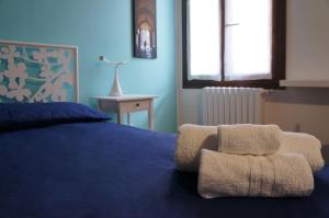 1 dormitorio con 1 cama azul y 2 toallas en La Scarana, en Ferrara