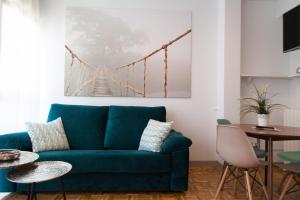 una sala de estar con un sofá azul y una pintura de puente en la pared en Apartamento City SOLO ADULTOS, en Madrid